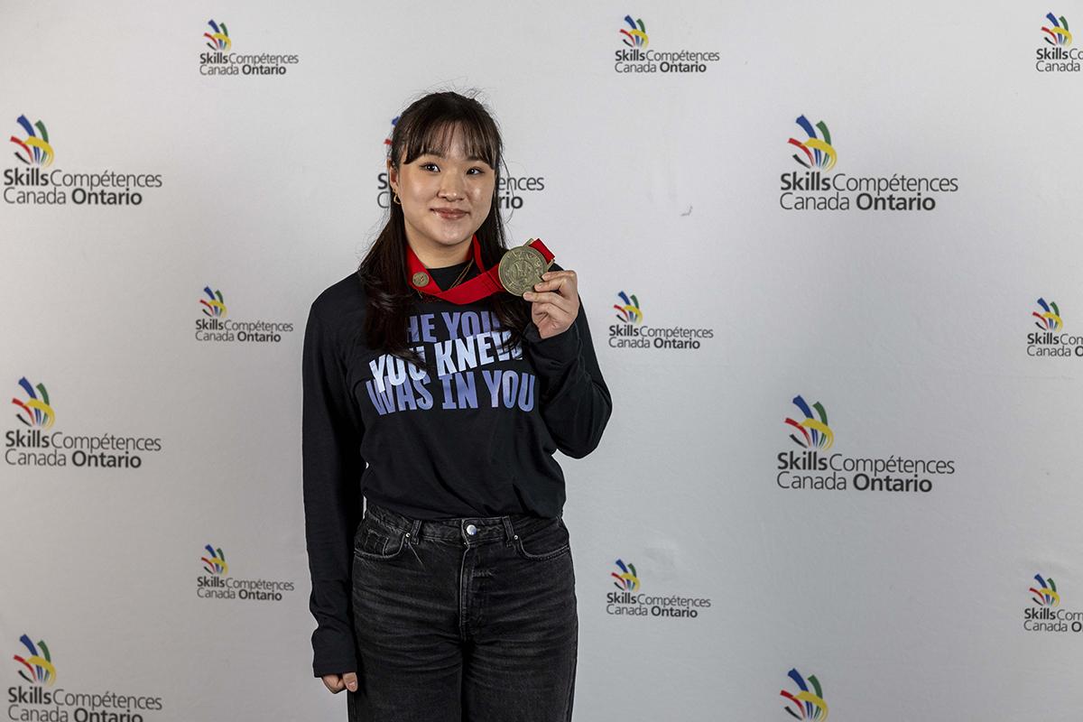 A person holds up a medal they’re wearing around their neck.